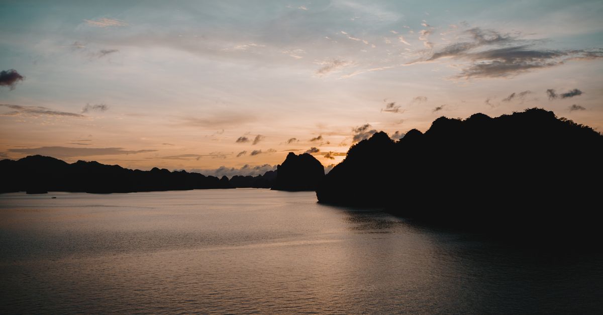 Tranquil sunset over Halong Bay, Vietnam with silhouette of limestone islands.